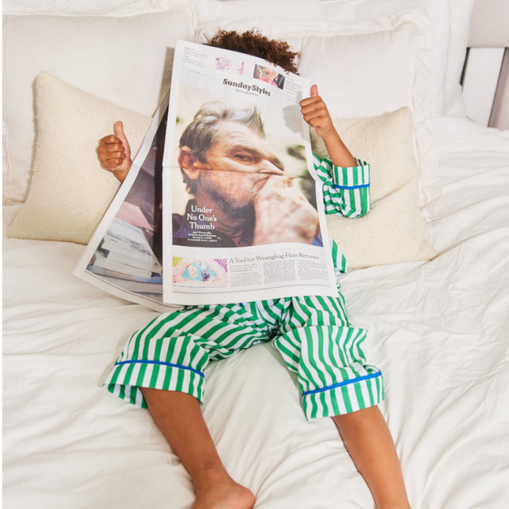 Kids green stripe pajama set by Midnight Palms featuring contrast piping, styled for a relaxed Sunday at home.
